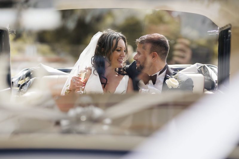 bride and groom  smooching in wedding car