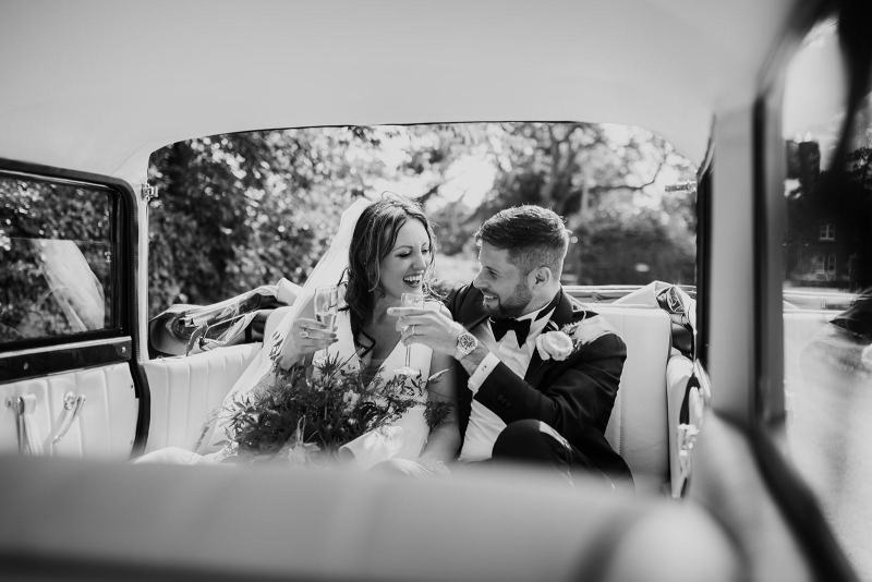 bride and groom  smooching in wedding car-black & white