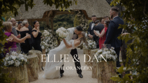 Dynamic outdoor wedding ceremony at The Orangery Maidstone; groom dipping the bride for a kiss as guests cheer.