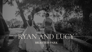 A black and white wedding photo at Braxted Park; the bride and groom are walking away holding hands and looking at each other in the early evening light of the grounds.