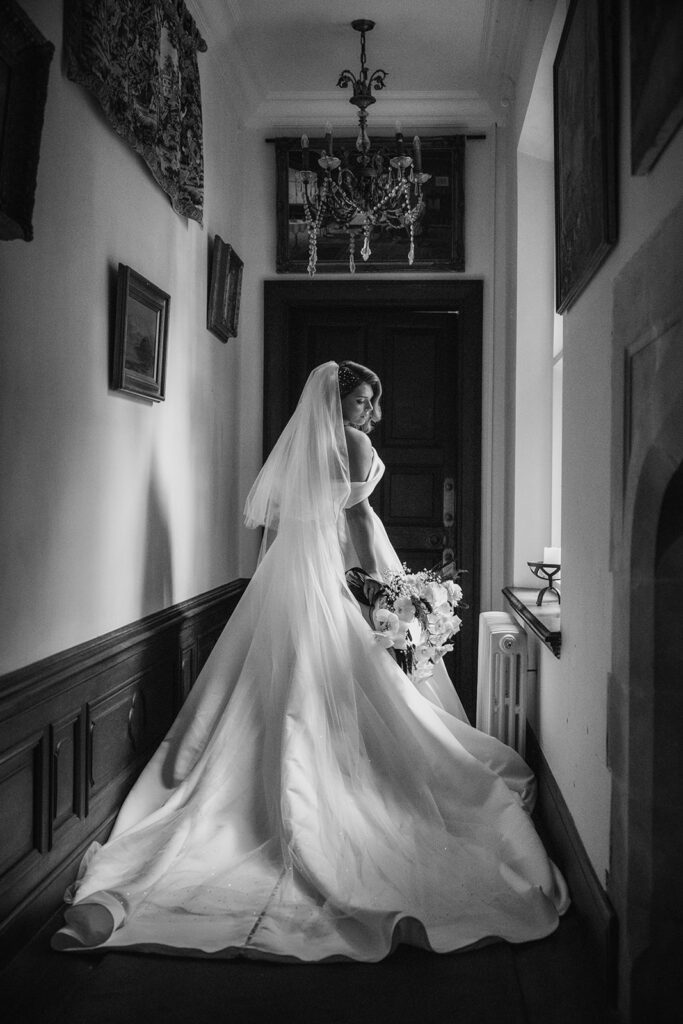 Creeksea Place wedding photographer; stunning bridal portrait in the hallway of Creeksea Place Essex; bride looking over her shoulder lit by natural window light.