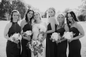 A candid black and white photo of the bridal party laughing and celebrating together at Apton Hall wedding venue.