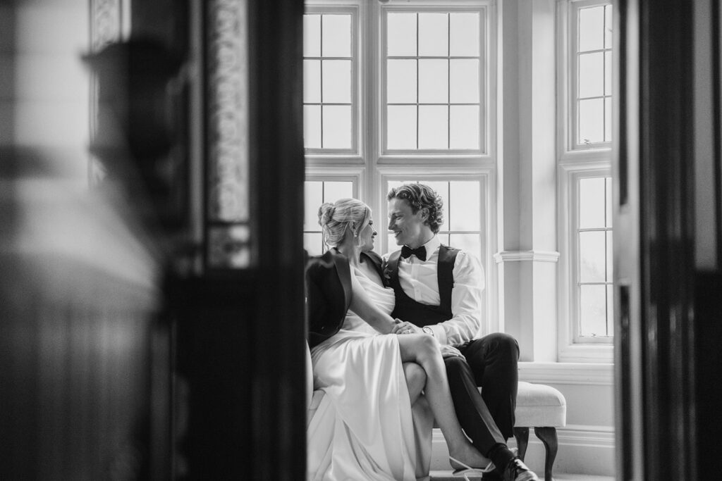 Landscape black and white wedding photography at Baddow Park House; editorial bride and groom portrait shot through a doorway; candid intimate couple photo Essex; Boutique Wedding